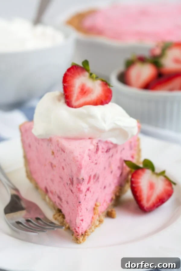 Close-up of a slice of Strawberry Icebox Pie, showcasing the vibrant pink filling and pretzel crust.