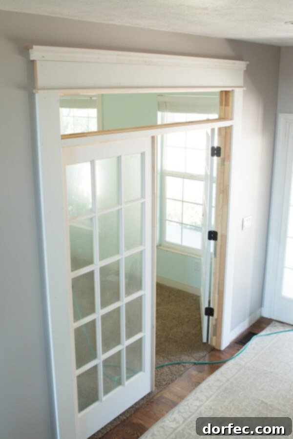 Newly installed French doors with transom above, enhancing light and creating a soft boundary for the home office.