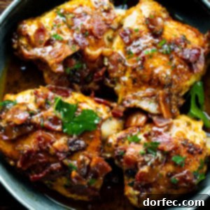 A photo of a skillet with 4 golden chicken thighs topped with bacon and chopped parsley