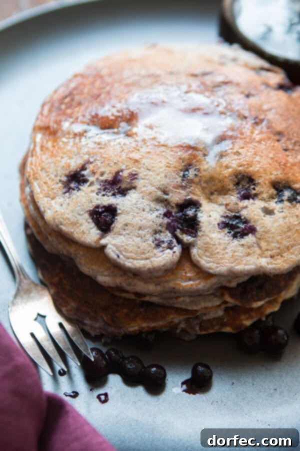 A close-up shot of a fluffy stack of healthy wild blueberry cottage cheese pancakes, highlighting their golden texture and the plump blueberries, ready for a guilt-free feast.