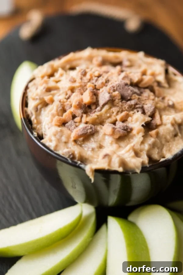 A beautifully composed shot of Toffee Apple Dip presented in a rustic bowl, surrounded by perfectly sliced green and red apples, ready for a gathering or sweet snack.