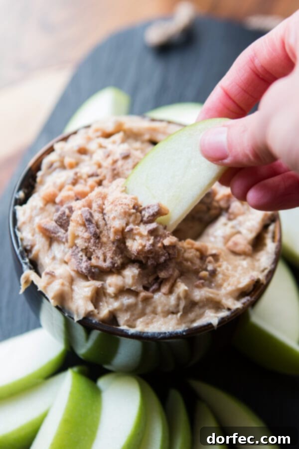 An overhead shot showcasing a bowl of Toffee Apple Dip, rich with brown sugar and milk chocolate toffee bits, surrounded by a generous spread of freshly sliced apples ready for dipping, creating an inviting snack.