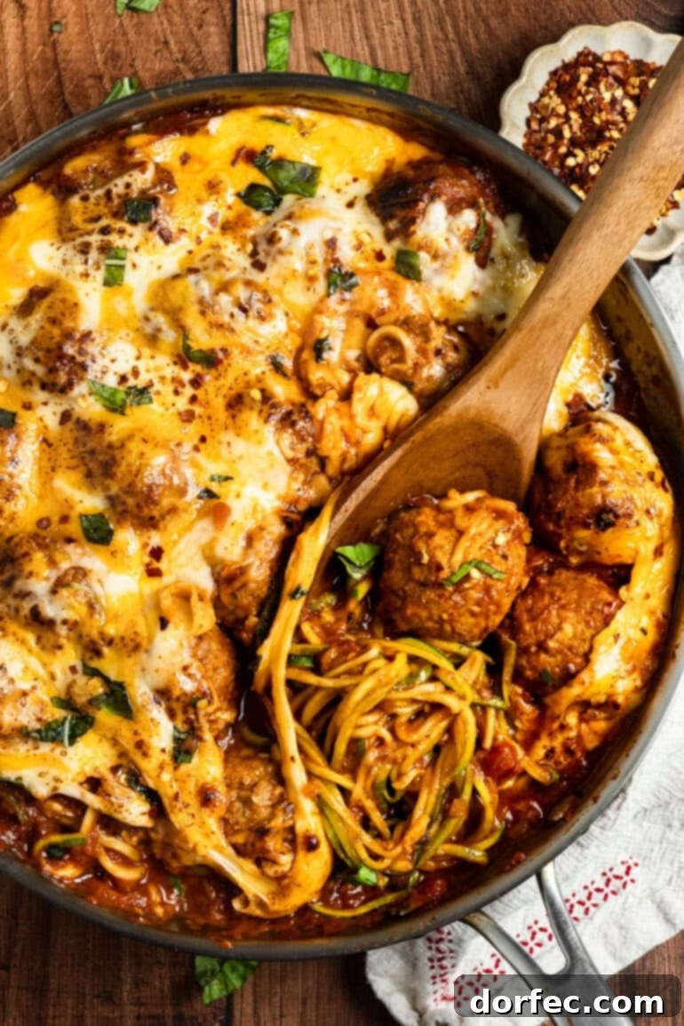 Hearty Cheesy Meatball and Zucchini Skillet 6 a photo of a skillet full of zoodles and meatballs cooking in a marinara sauce.