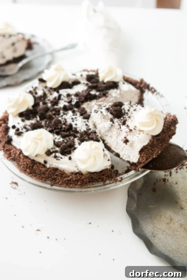 A serving spoon lifting a perfect slice of homemade No-Bake Oreo Pie with its rich chocolate graham cracker crust, ready to be enjoyed.