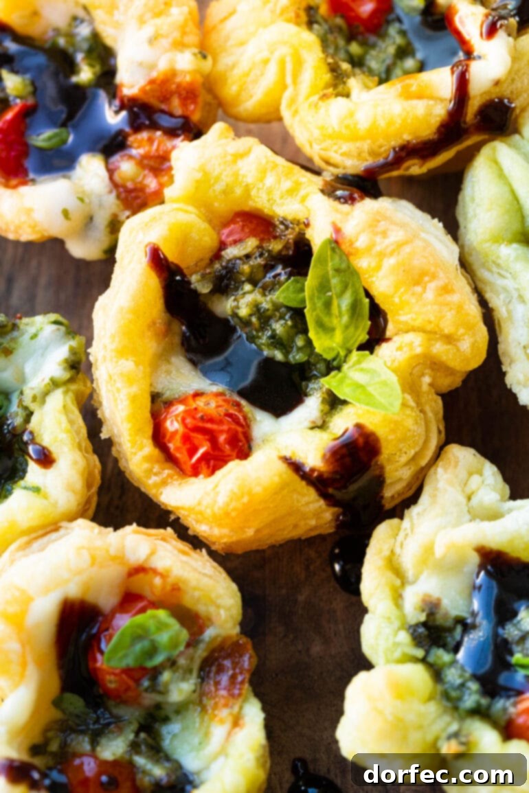 a photo of a golden crispy pesto puff pastry bite topped with a balsamic glaze and fresh basil