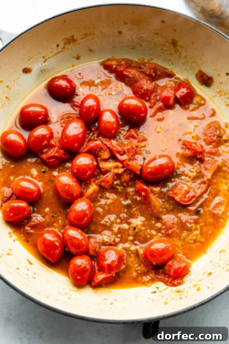 A visual guide showing grape tomatoes being halved, ready to be added to the skillet, ensuring even cooking and flavor distribution in the pesto pasta.