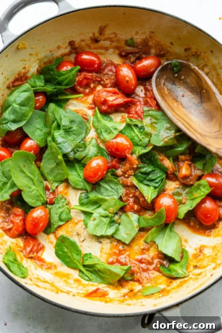 A photo gallery showcasing the crucial steps of sautéing garlic, juicy grape tomatoes, fresh spinach, and aromatic basil leaves in a large skillet, building the foundational flavors for the quick pesto pasta.