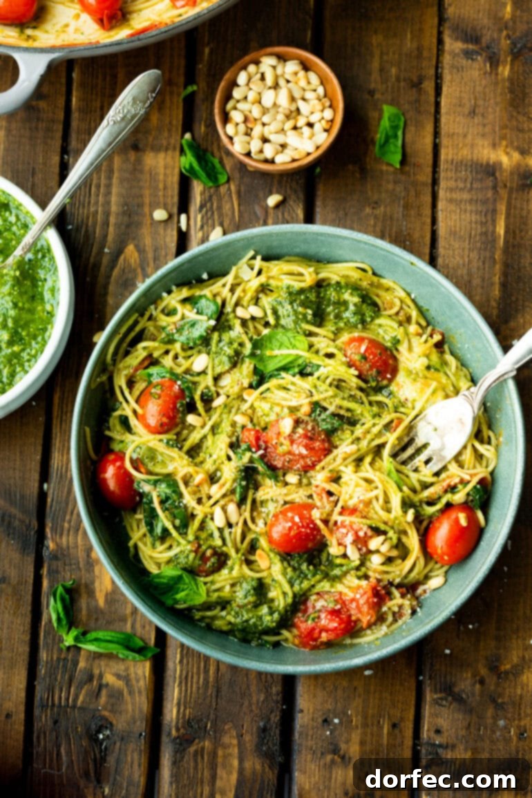 A beautifully composed photo featuring a large bowl of luscious pesto pasta, accompanied by a smaller bowl of vibrant green pesto and another bowl of golden, toasted pine nuts, ready for garnishing.