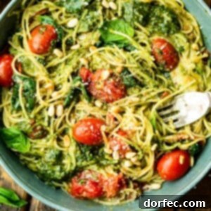 A delicious bowl of 20-minute cheesy pesto pasta, garnished with fresh basil and grape tomatoes, showcasing a perfect weeknight meal.