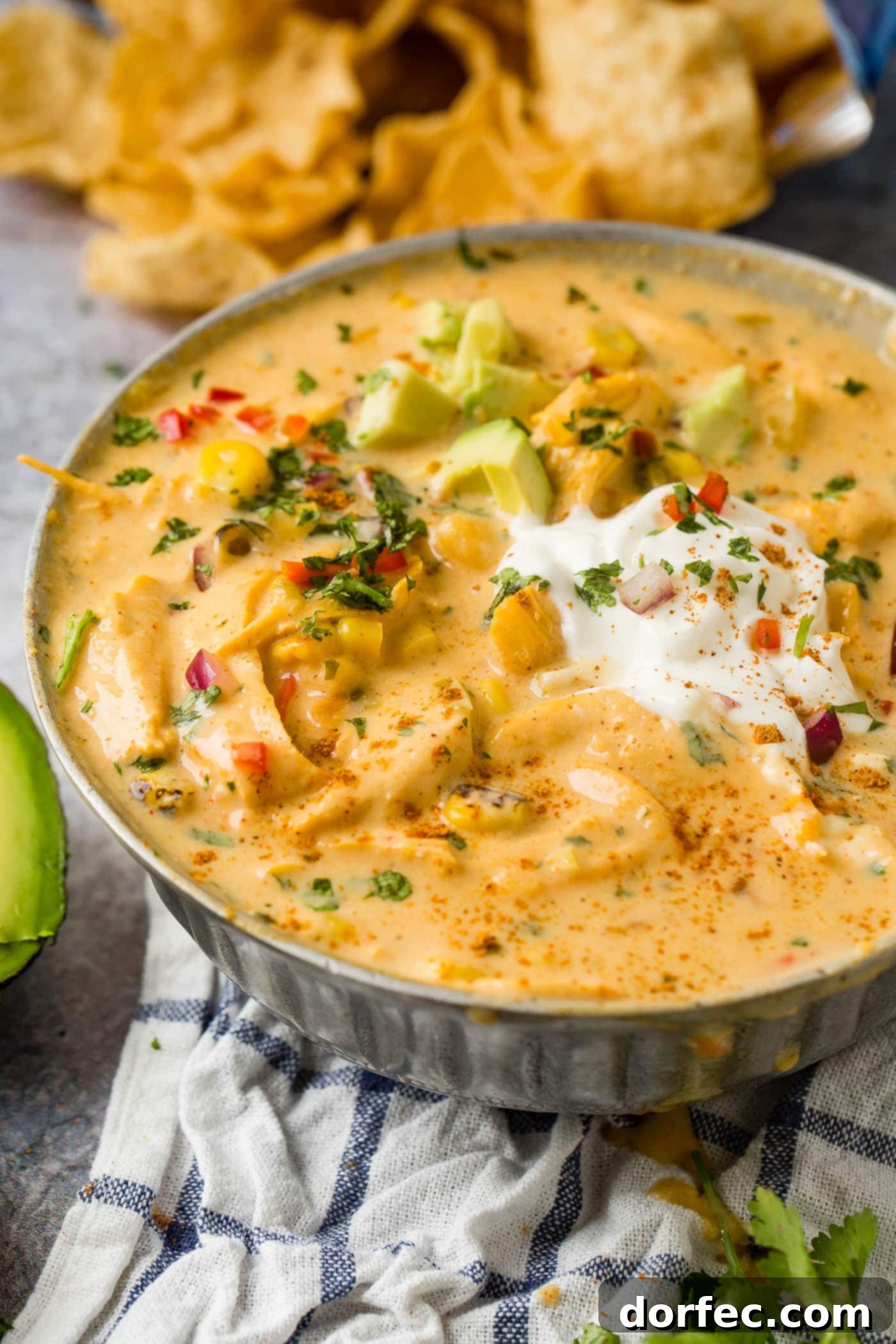 A visually appealing bowl of cheesy chicken tortilla soup, garnished with dollops of sour cream and fresh avocado slices, promising a delightful culinary experience.