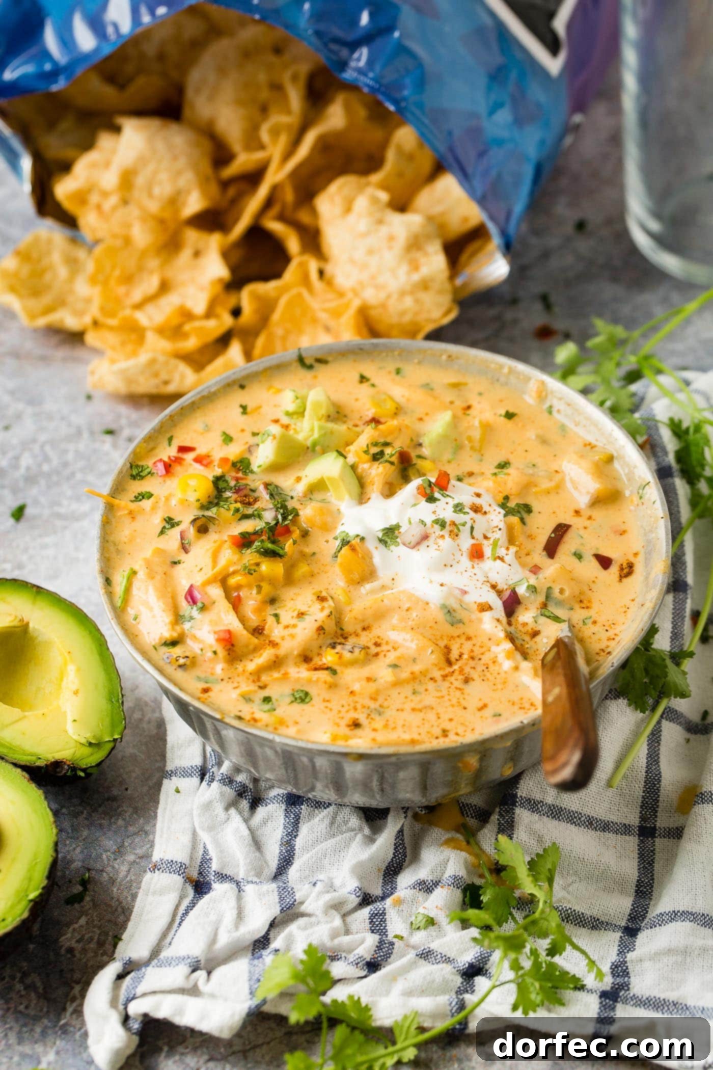 A hearty bowl of cheesy chicken tortilla soup, garnished with creamy sour cream and fresh avocado, emphasizing its rich and inviting nature.