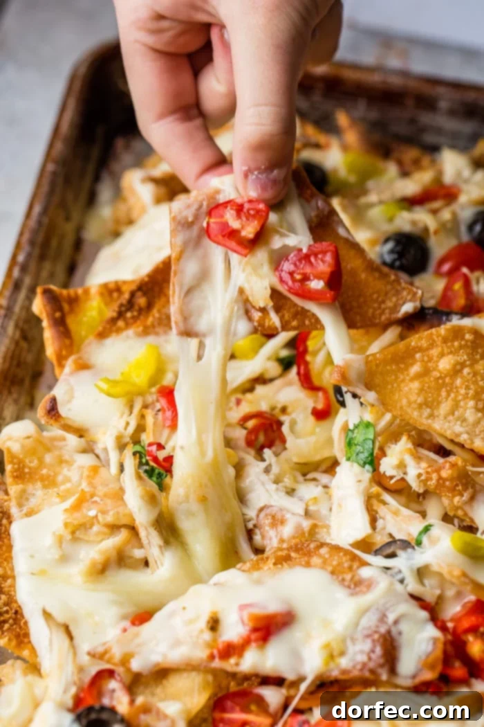 A close-up shot of homemade Italian Nachos, showcasing the melted mozzarella, tender chicken, and vibrant peppers atop golden wonton chips.