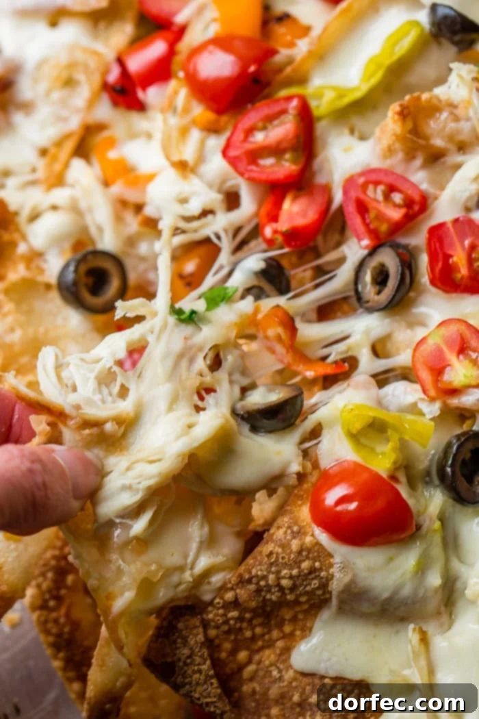 A vibrant platter of Italian Nachos, ready for a party, featuring melted cheese, shredded chicken, and colorful peppers on golden wonton chips.