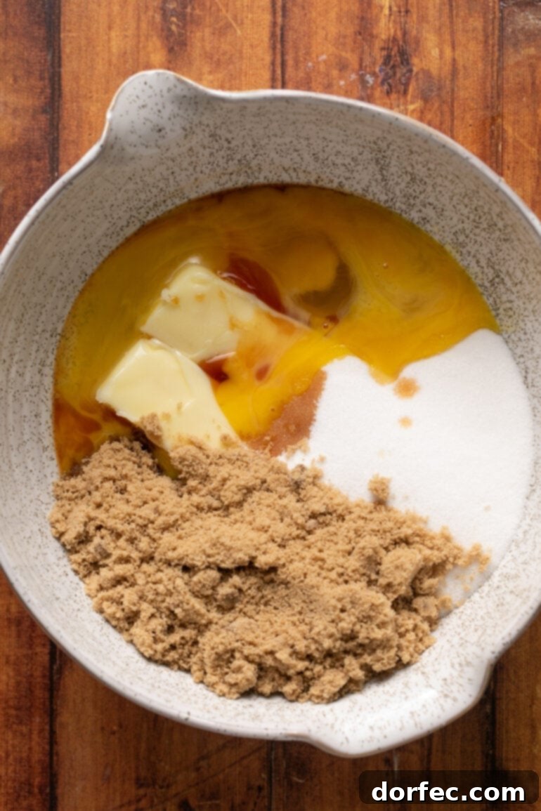 A step-by-step photo of combining softened butter, granulated sugar, and brown sugar in a large mixing bowl, illustrating the initial creaming process for the cookie dough.