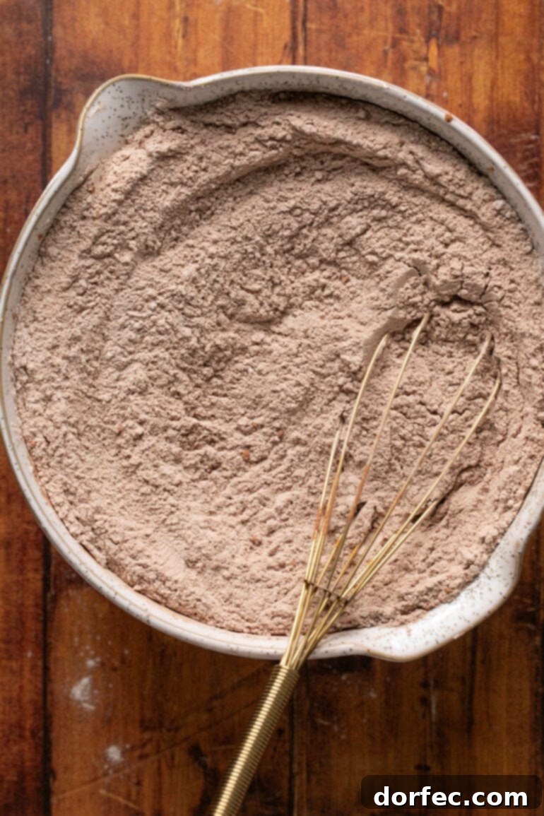 A bowl containing all the dry ingredients for the chocolate cookies—flour, cocoa powder, baking soda, salt, and instant pudding mix—whisked together until perfectly blended.