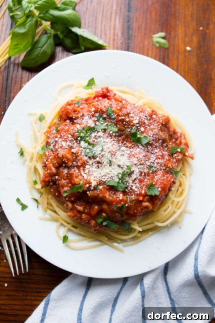 pasta topped with homemade spaghetti sauce and grated parmesan on white plate