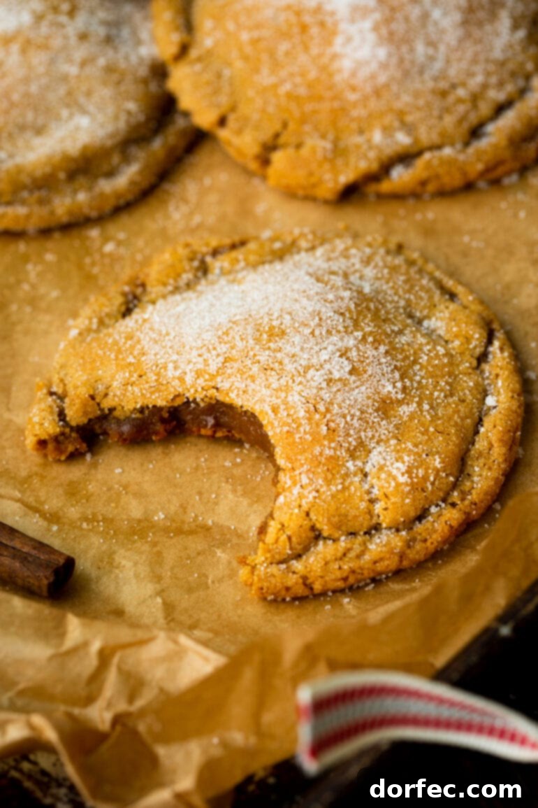 A close-up shot of a large, chewy molasses cookie, featuring a bite taken out and generously sprinkled with granulated sugar.