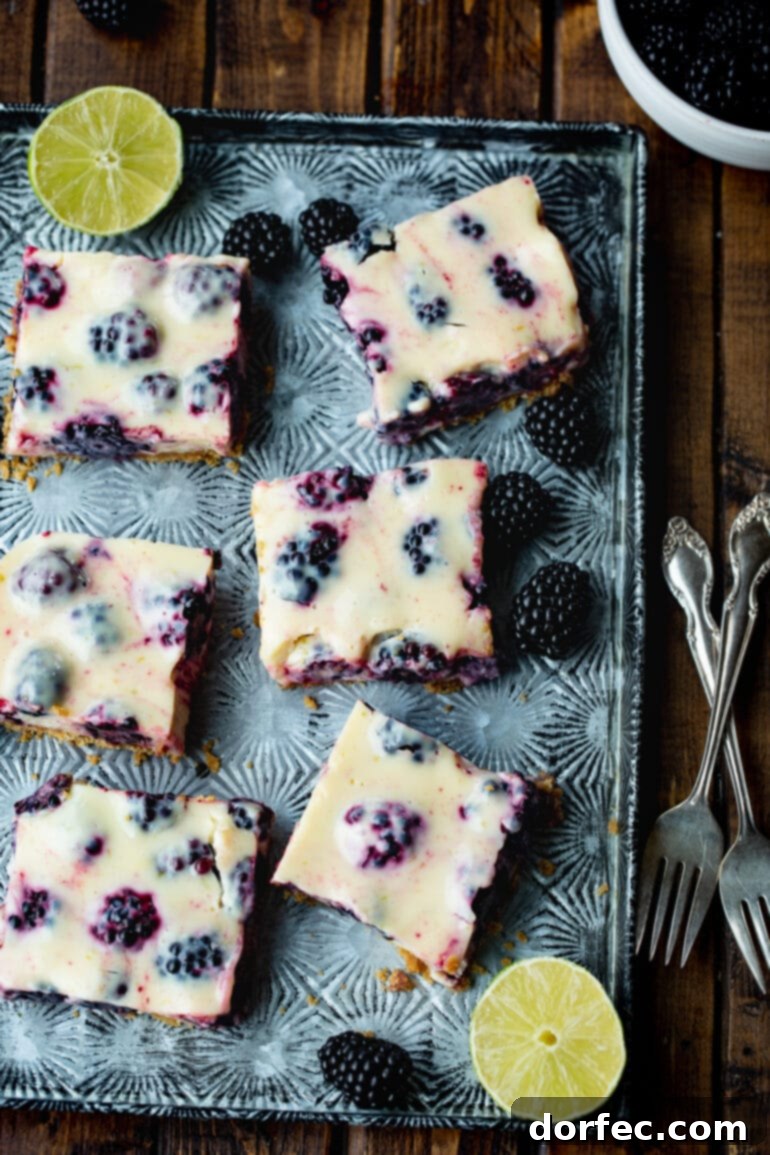 Effortless Blackberry Lime Bars 6 Several perfectly cut blackberry lime bars displayed on a sleek metal serving tray, artfully arranged with whole, fresh blackberries scattered around them.