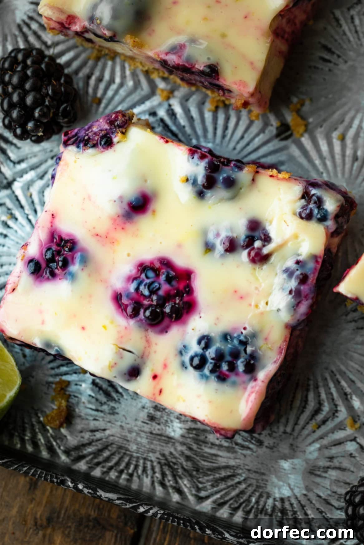 Effortless Blackberry Lime Bars 7 A close-up shot of a single blackberry lime bar, highlighting its creamy filling, crunchy graham cracker crust, and the abundance of fresh, juicy blackberries within.