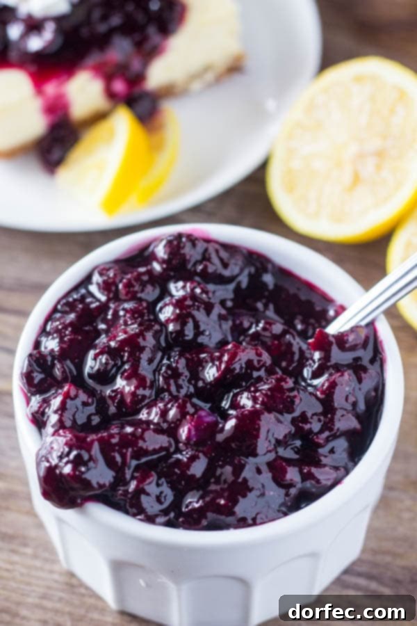Luscious Lemon Blueberry Cheesecake Bars Overhead view of several lemon blueberry cheesecake squares with a spoonful of blueberry sauce