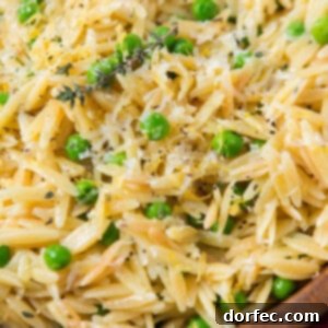 Delicious and Quick and easy lemon orzo with parmesan and peas in a wooden bowl.