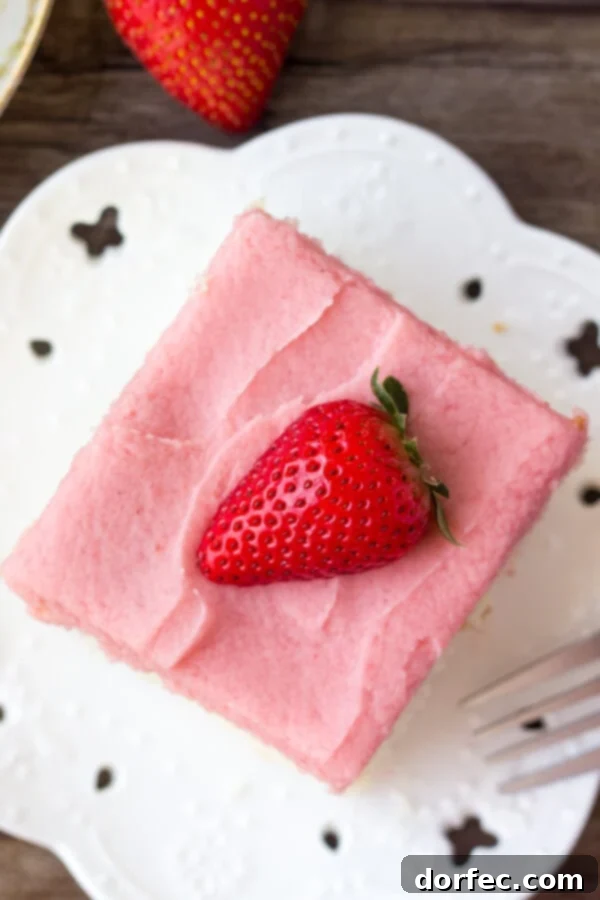 Soft, moist vanilla sheet cake topped with strawberry buttercream - you'll love the flavor combo and pretty pink color of this vanilla cake with fresh strawberry frosting. Fresh strawberries and baking ingredients laid out for making the vanilla cake and strawberry frosting.