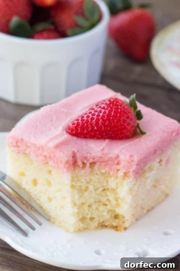 Soft, moist vanilla sheet cake topped with strawberry buttercream - you'll love the flavor combo and pretty pink color of this vanilla cake with fresh strawberry frosting. A beautifully frosted slice of vanilla cake with strawberry buttercream, showing its moist texture.