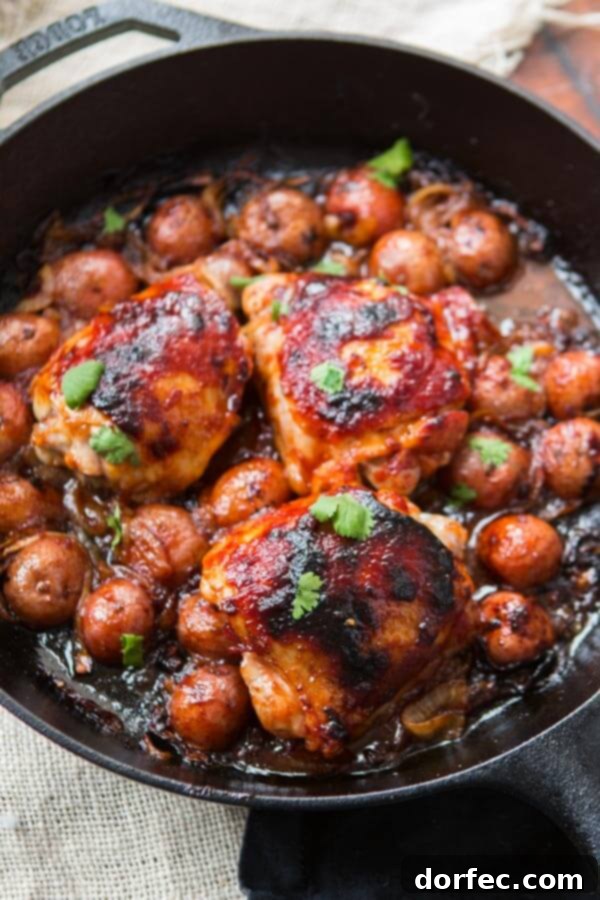 Close-up of a pan of one-skillet BBQ chicken and potatoes, showcasing perfectly roasted potatoes, caramelized onions, and tender chicken. Ideal for a make-ahead dinner.