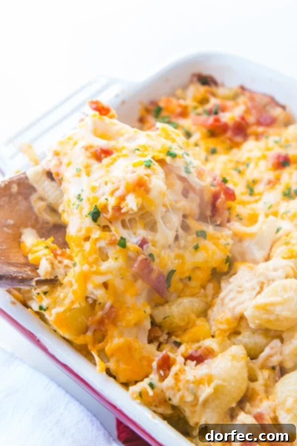 Enjoying a serving of this quick and easy Cheesy Chicken Bacon Ranch Casserole, a favorite for kids! A serving of Cheesy Chicken Bacon Ranch Casserole being scooped out, showcasing the pasta, chicken, bacon, and melted cheese.