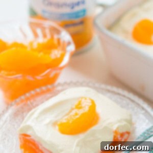 Sunshine Citrus Gelatin Delight 3 Vibrant orange jello salad with a creamy lemon topping, garnished with fresh mandarin oranges, ready to serve.