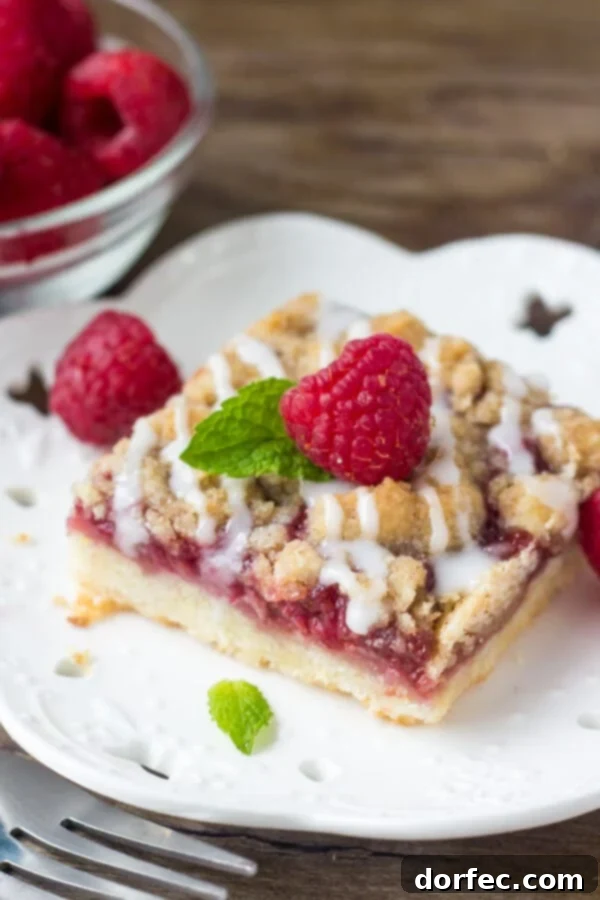 A close-up shot of delicious raspberry crumble bars, showcasing the shortbread base, juicy raspberry filling, and crunchy topping, ready to be enjoyed.