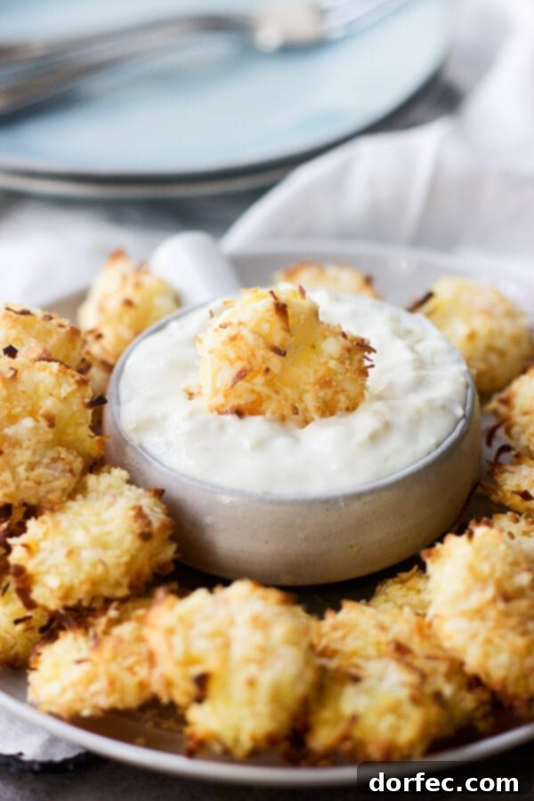 One Pot Crispy Parmesan Shrimp Scampi Pasta 8 Crispy golden baked coconut shrimp piled high, accompanied by a small bowl of bright tropical dipping sauce, ready for a delicious bite.