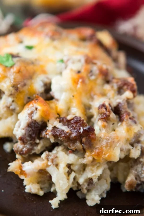 A delicious serving of cheesy hash brown sausage breakfast casserole, ready to enjoy. portion of cheesy hash brown sausage breakfast casserole on gray plate, garnished with parsley