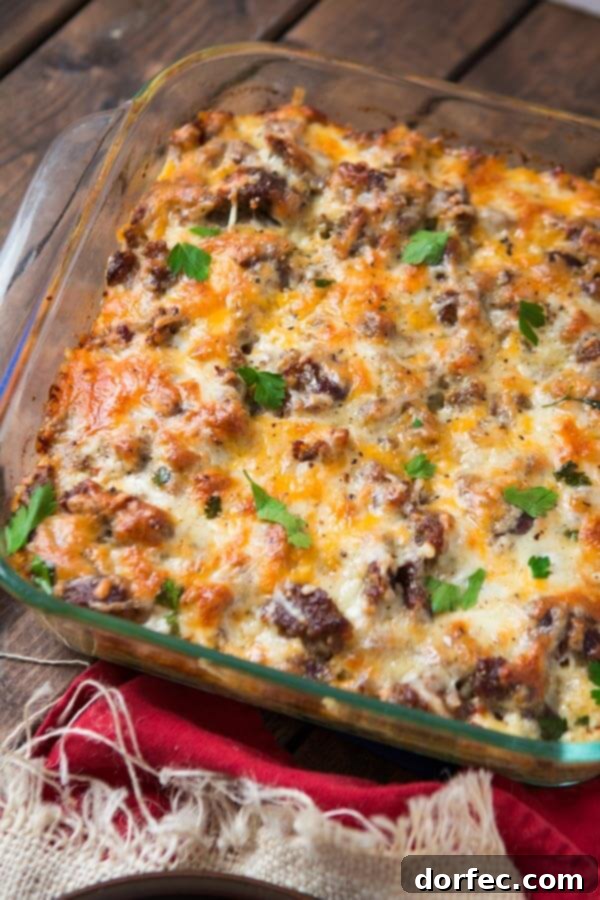 A family-sized cheesy hash brown sausage breakfast casserole for any occasion. sausage hashbrown breakfast casserole in square glass baking dish, sliced and ready to serve