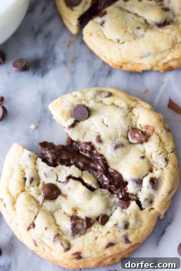 A freshly baked fudge-filled chocolate chip cookie, cracked open to show the soft, melty chocolate fudge within