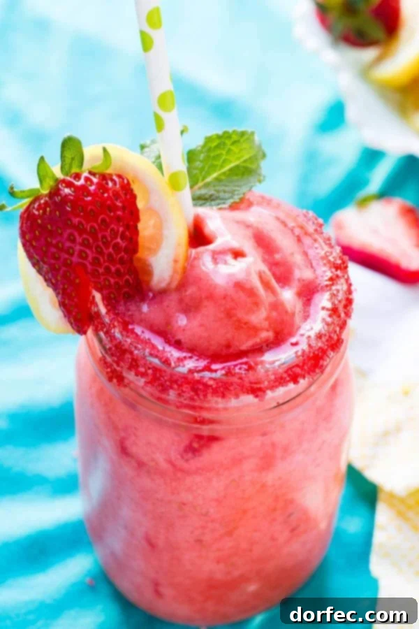Delicious 2-Minute Frozen Strawberry Lemonade with Wholesome Organic Stevia A tall glass of vibrant pink frozen strawberry lemonade, garnished with fresh strawberries and bright lemon slices, glistening under the summer sun.