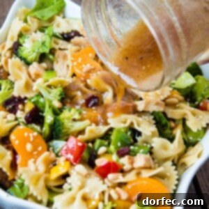 A close-up of the finished Teriyaki Chicken Pasta Salad with sesame dressing, featuring pasta, chicken, mandarin oranges, and various vegetables. ohsweetbasil.com