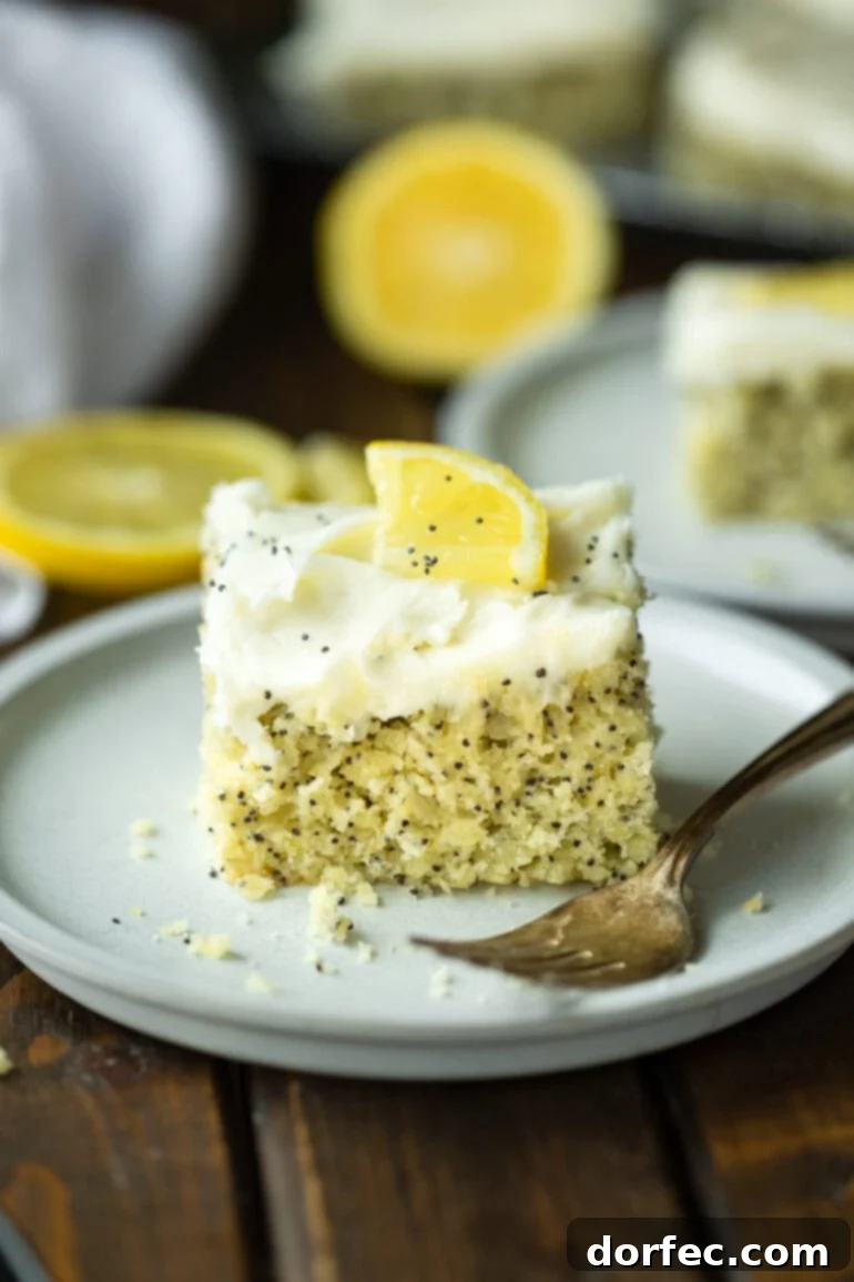 Zesty Lemon Poppy Seed Cake with Velvety Cream Cheese Frosting 2 a photo of a piece of lemon poppy seed cake topped with a white cream cheese frosting and small lemon slice