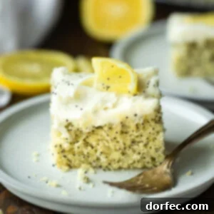 Zesty Lemon Poppy Seed Cake with Velvety Cream Cheese Frosting 7 a photo of a piece of lemon poppy seed cake topped with a white cream cheese frosting and small lemon slice