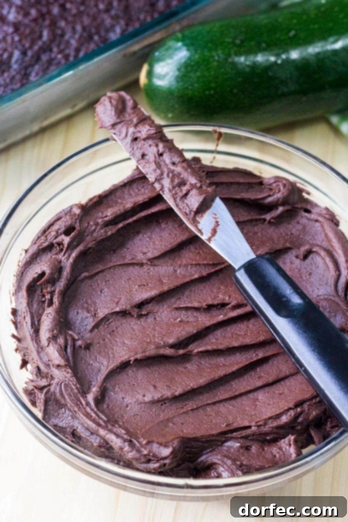 A bowl filled with rich, creamy homemade chocolate frosting, with a knife resting on top, ready for spreading.