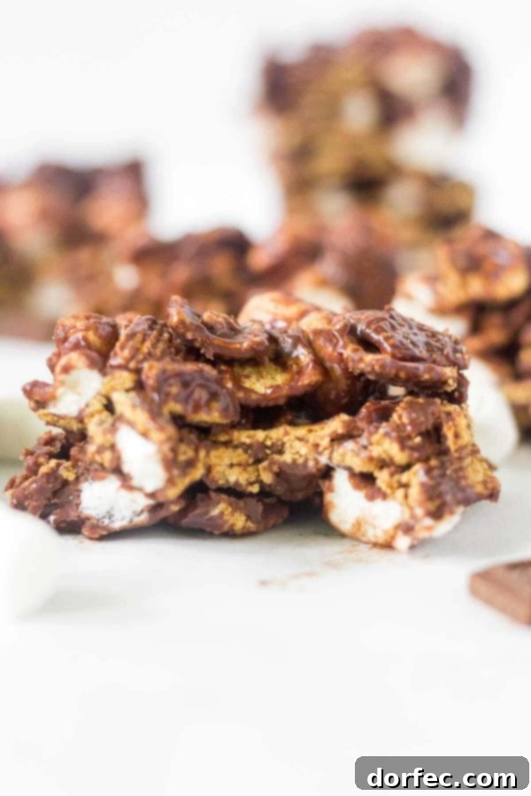 Learn how to make no bake s'mores bars at home! This simple recipe calls for 4 ingredients and takes under 15 minutes to come together. This summer dessert recipe is so yummy and easy you'll want to make it every week. Hershey's chocolate, mini marshmallows, Golden Grahams