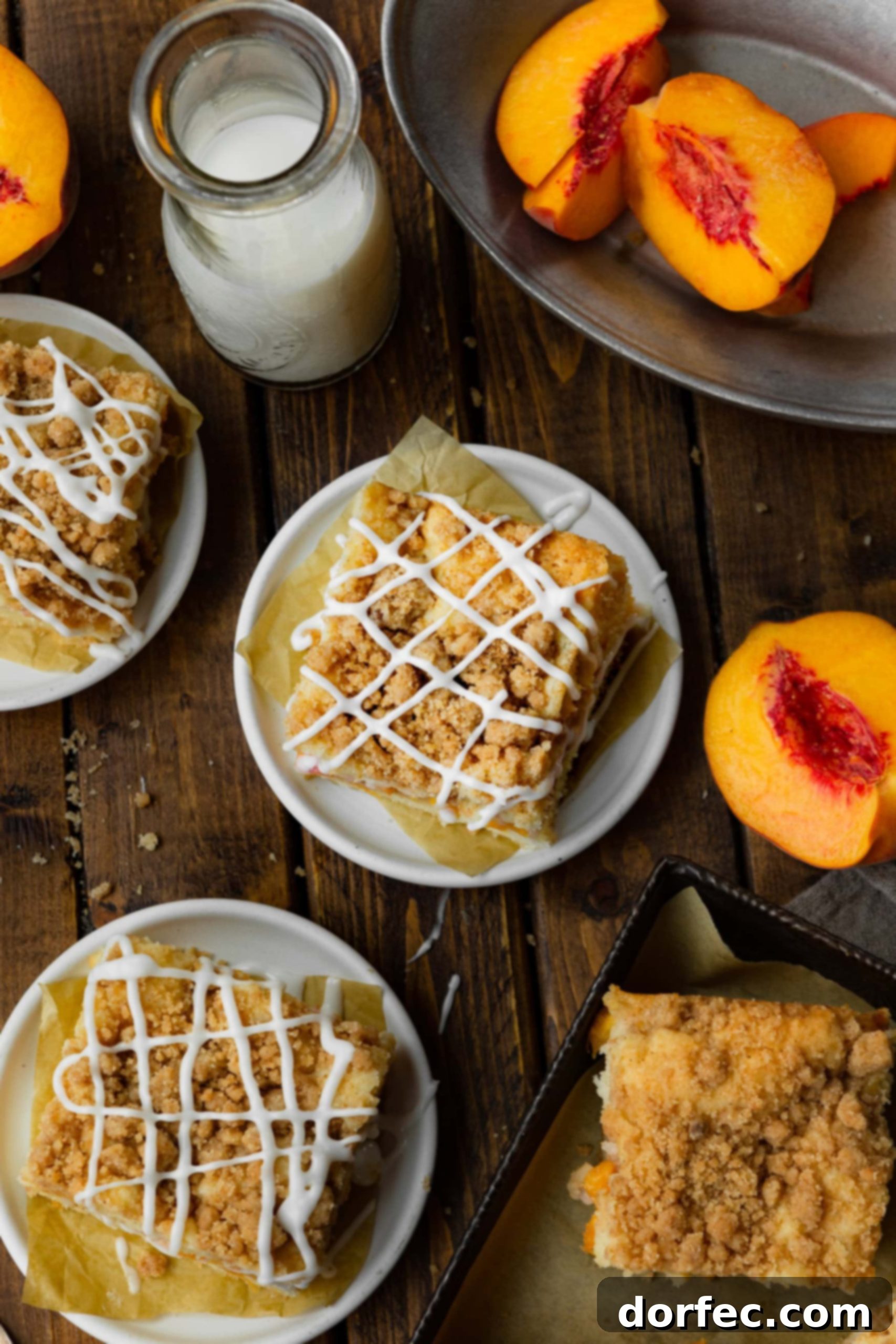 An overhead shot showcasing multiple slices of peach coffee cake, each adorned with a generous cinnamon streusel topping and delicate vanilla glaze drizzle, arranged on small dessert plates.