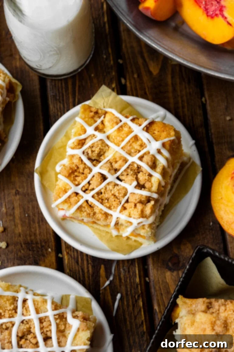 An inviting aerial view of a slice of peach coffee cake, featuring its luscious streusel topping and elegant vanilla glaze drizzle, ready to be enjoyed.