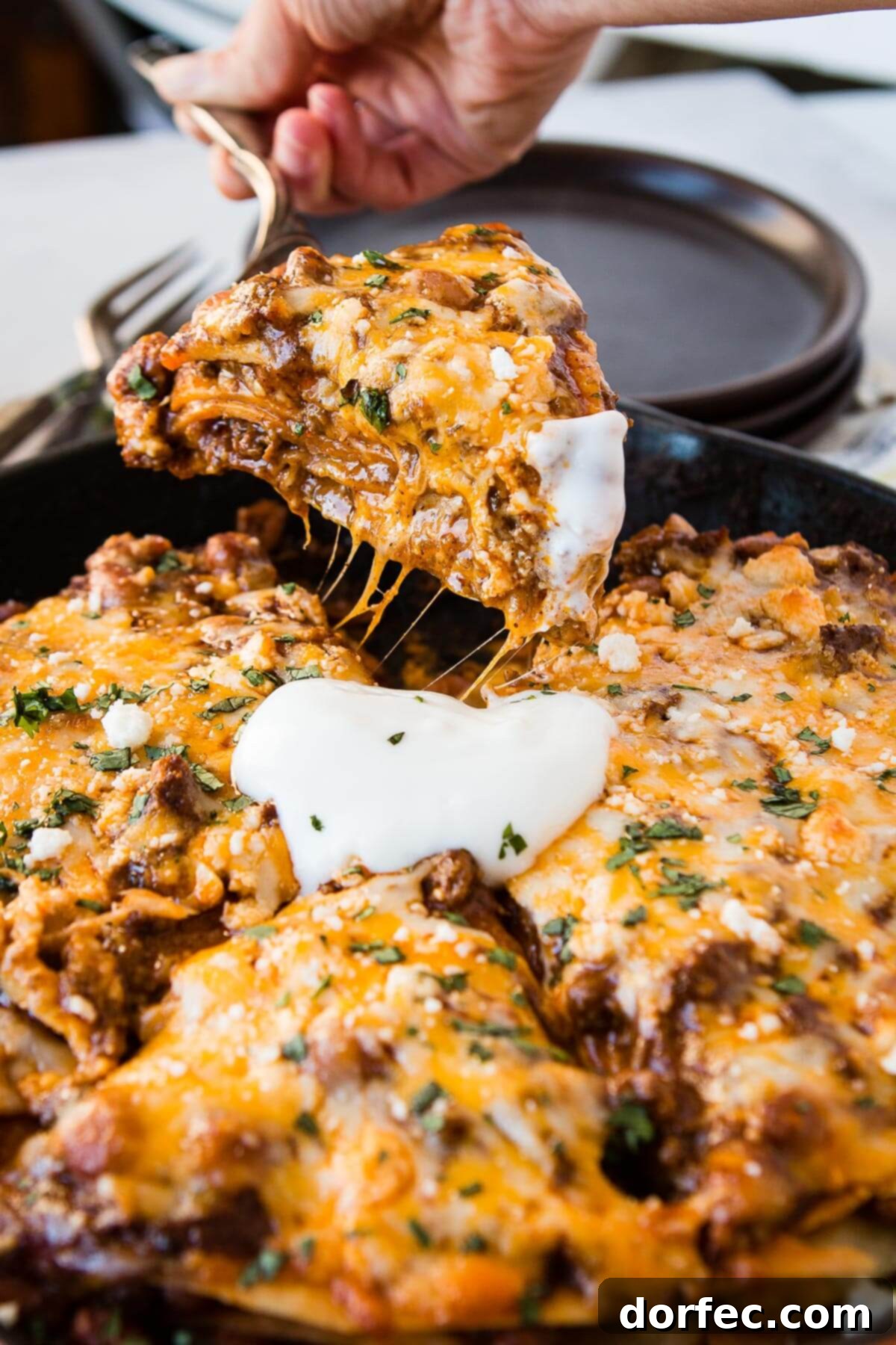 Quick One Skillet Ground Beef Enchilada Dinner 3 A photo of someone expertly removing a generous slice of steaming enchilada casserole from a cast iron skillet, showcasing its delicious layers.