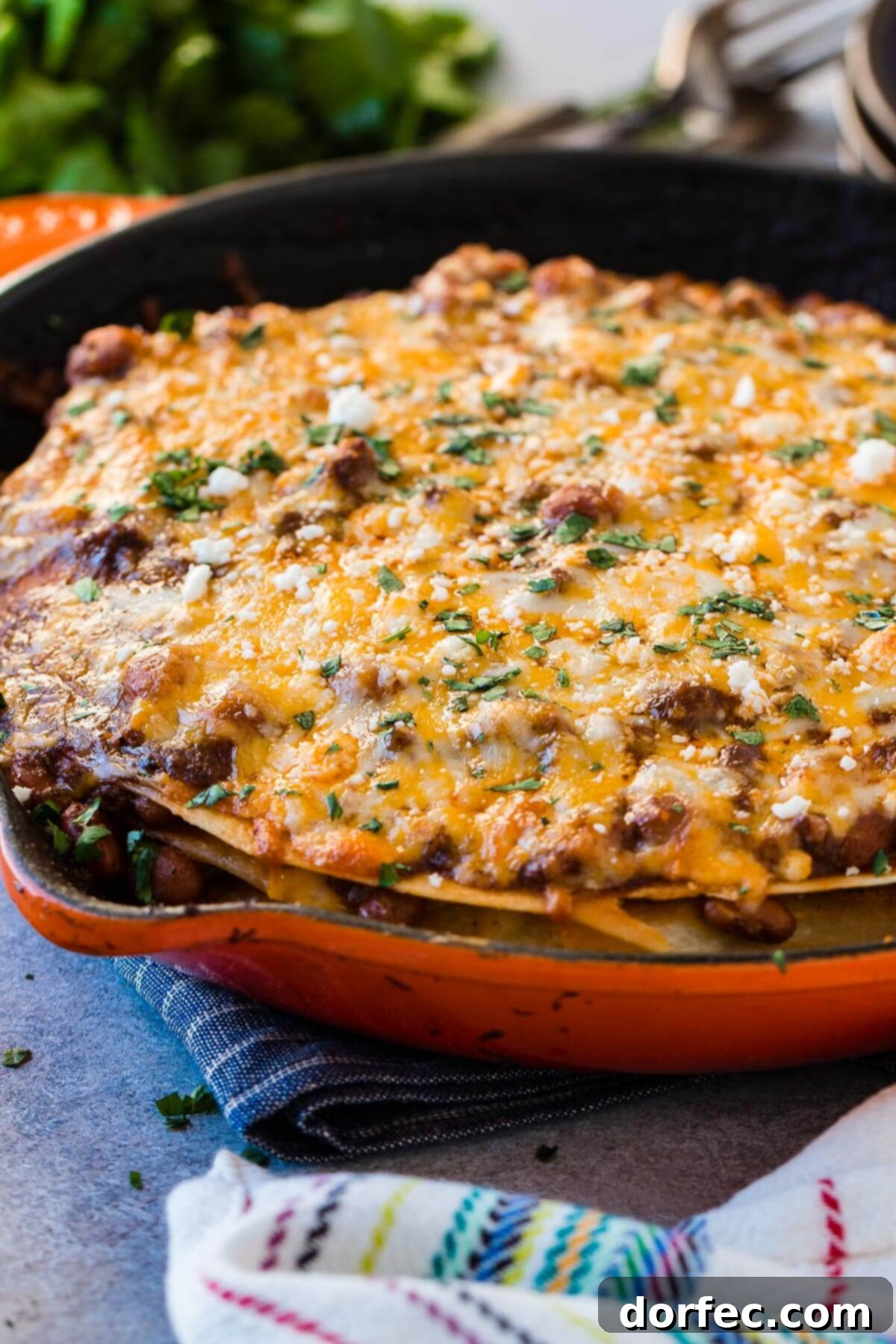Quick One Skillet Ground Beef Enchilada Dinner 5 A wide-angle photo of a cast iron skillet filled with bubbling ground beef enchilada casserole, generously topped with golden melted cheese.