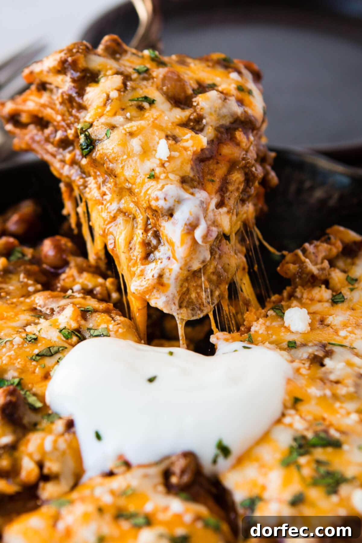 Quick One Skillet Ground Beef Enchilada Dinner 7 A close-up action shot of a serving of enchilada casserole being lifted out of the pan, revealing its delicious layers.