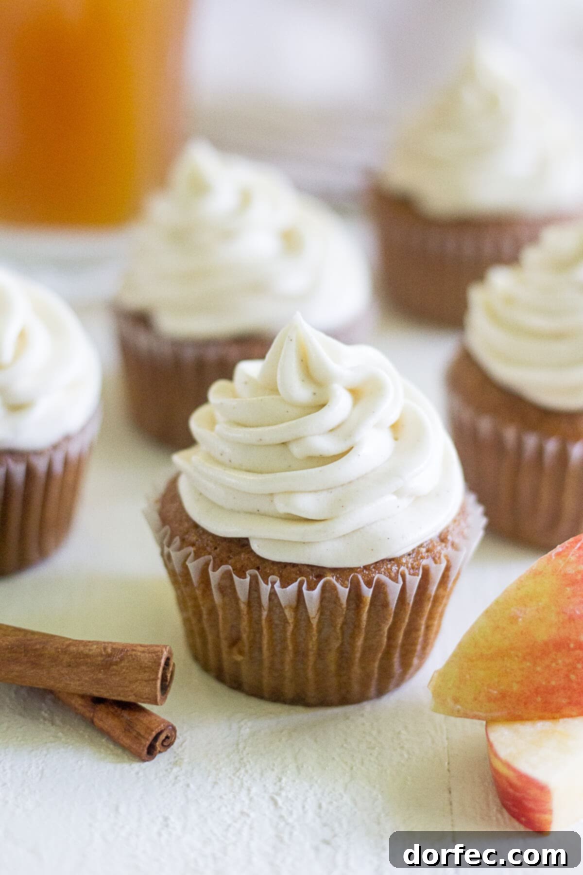 five apple cider cupcakes frosted with a swirl of cinnamon cream cheese frosting, evoking a cozy fall feeling
