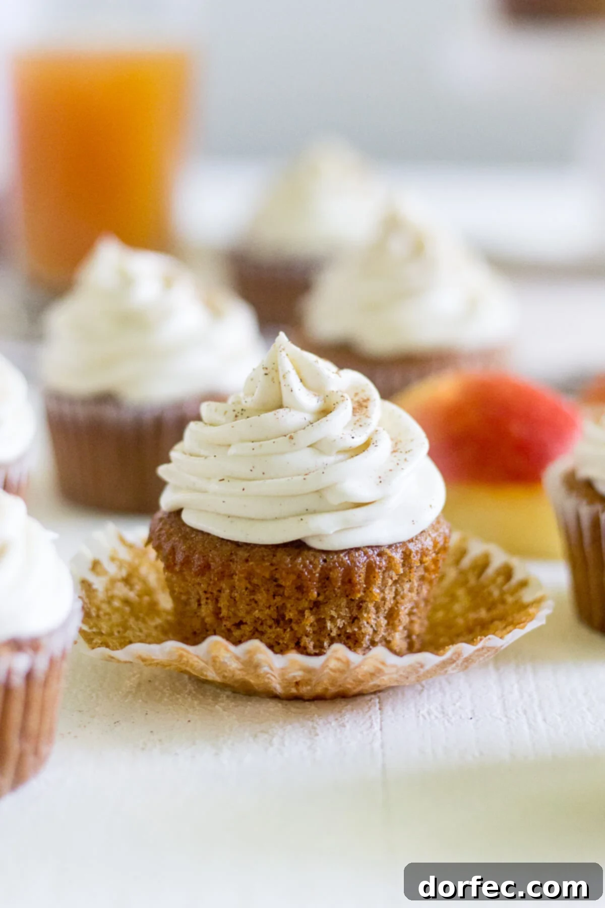 a row of apple cinnamon cupcakes, with the front one having its liner peeled down to reveal the soft, spiced cake