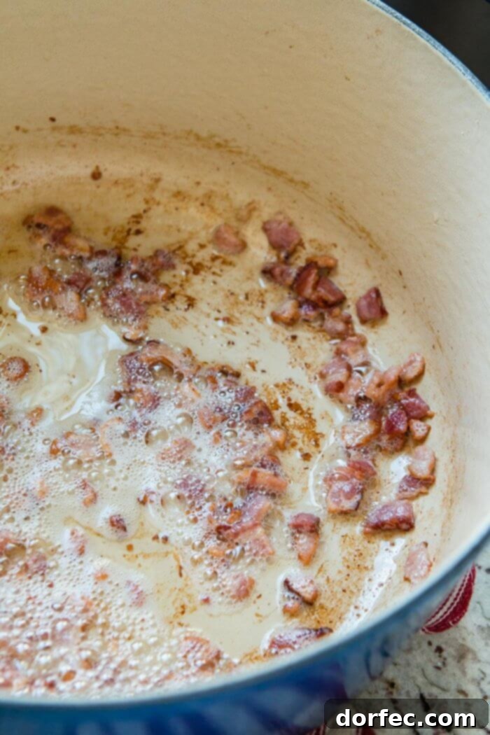 Bacon sizzling in a Dutch oven, creating a flavorful base for the rich and savory One Pot Cauliflower Chowder.