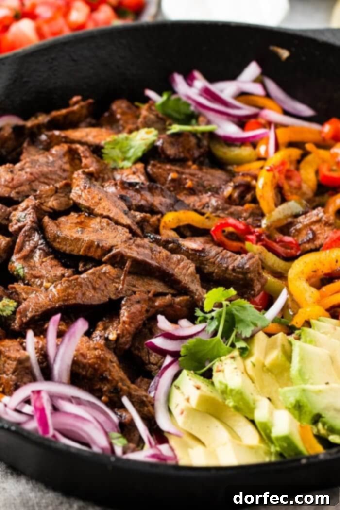 The Ultimate Steak Fajita Marinade 2 Sizzling steak fajitas with colorful peppers and onions in a cast iron skillet, ready to be served.